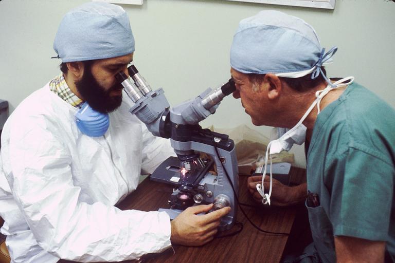Two researchers looking through microscopes.