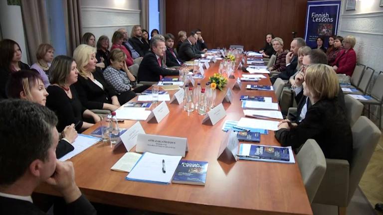 A group of people sitting around a table with a large number of documents.