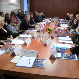 A group of people sitting around a table with a large number of documents.